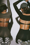 Back view of model two models posing in sueded onyx and sueded essex bra and legging sets