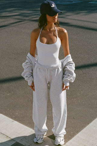 Full body front view of model posing outside in the street in the fitted and smoothing sueded white Halter Scoop Tank with a scoop neckline, open back and narrow, adjustable neck strap