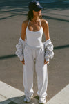 Full body front view of model posing outside in the street in the fitted and smoothing sueded white Halter Scoop Tank with a scoop neckline, open back and narrow, adjustable neck strap