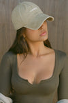 Front view of model posing in the six-panel desert Official Cap with a curved brim and an embroidered upside down Joah Brown logo on the front