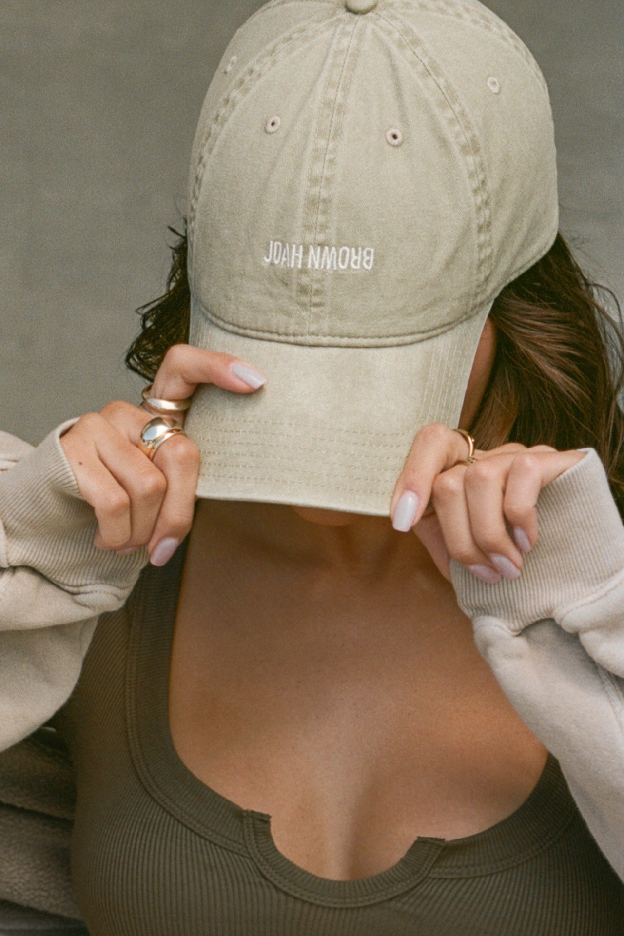 Close up front view of model posing in the six-panel desert Official Cap with a curved brim and an embroidered upside down Joah Brown logo on the front