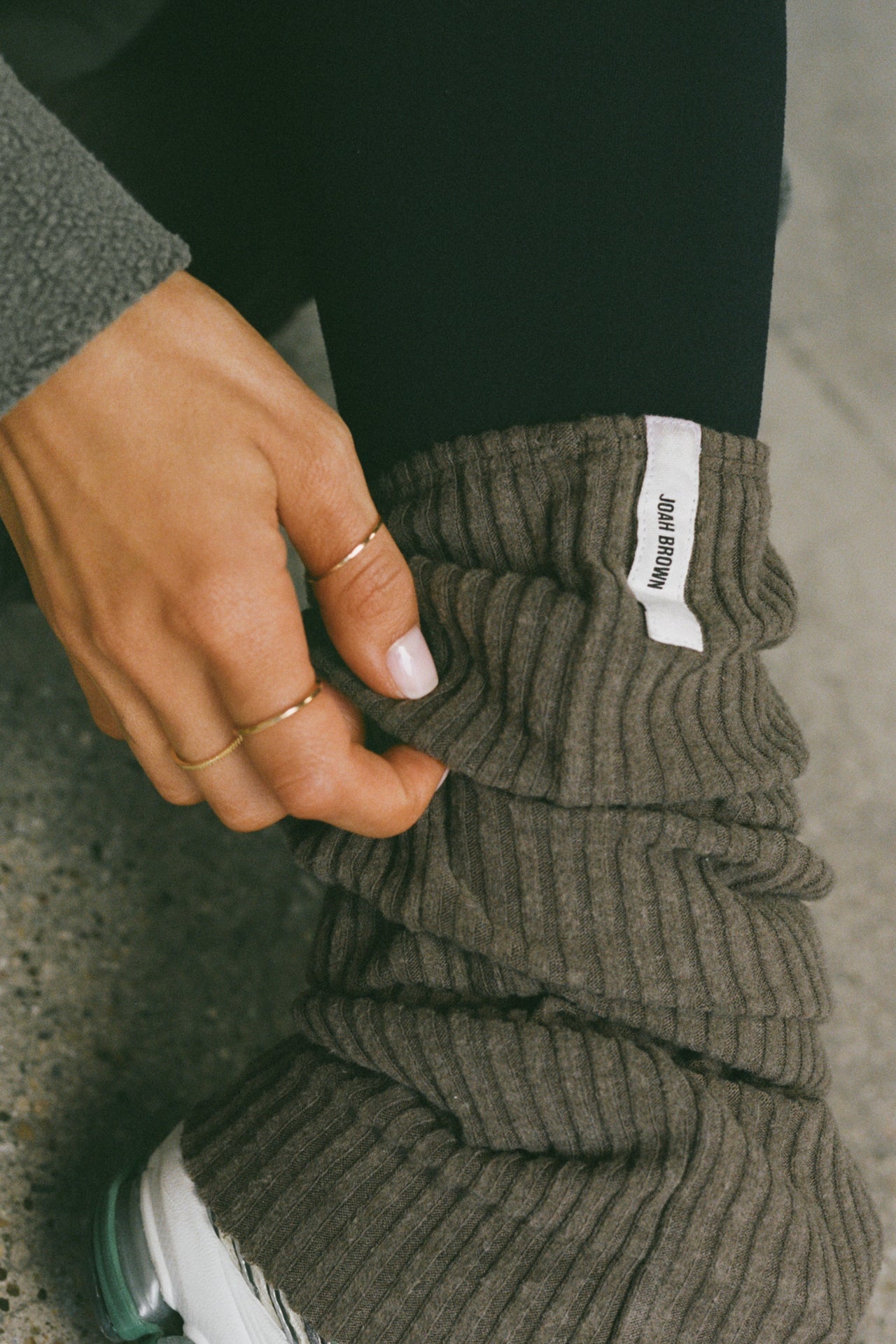 Close up side view of model adjusting the slouchy, pull on army luxe knit Leg Warmers that can be worn pulled up on scrunched down