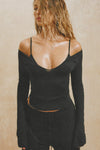 Front view of model posing in the fitted black modal Notched V Neck Long Sleeve top with a deep notched V-neckline, extra long sleeves and small side slits at the hem