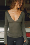 Front view of model posing in the fitted spruce Notched V Neck Long Sleeve top with a deep notched V-neckline, extra long sleeves and small side slits at the hem