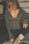 Front view of model posing in the fitted spruce Notched V Neck Long Sleeve top with a deep notched V-neckline, extra long sleeves and small side slits at the hem