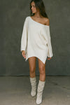 Full body front view of model posing in the relaxed fit natural luxe knit Off Shoulder Tunic with a wide off-the-shoulder neckline and asymmetrical hem