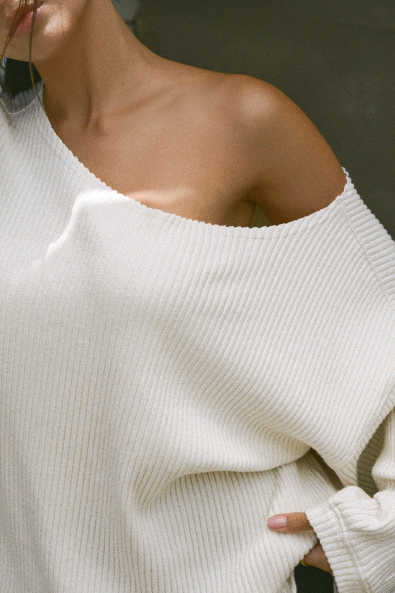 Close up detail front view of model posing in the relaxed fit natural luxe knit Off Shoulder Tunic with a wide off-the-shoulder neckline and asymmetrical hem
