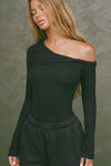 Front view of model posing in the fitted black rib Off Shoulder Twist Long Sleeve top asymmetrical neckline with a twist detail and off-shoulder design