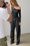View of a photographer taking a full body  photo of a model posing in the fitted black rib Off Shoulder Twist Long Sleeve top asymmetrical neckline with a twist detail and off-shoulder design