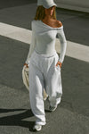 Full body front of model posing outside in the street in the relaxed fit pearl grey french terry Oversized Straight Leg Jogger with an elastic waistband, hidden drawstring, pocket details. and adjustable cinching at the ankle cuffs