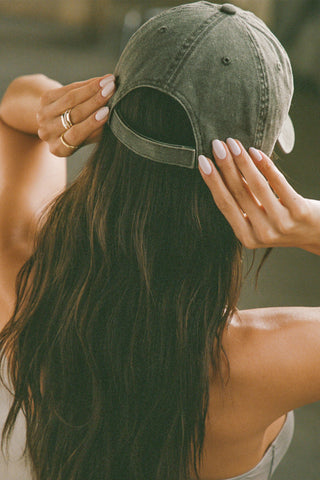 Back view of model wearing the six-panel washed green Official Cap with a curved brim and adjustable strap