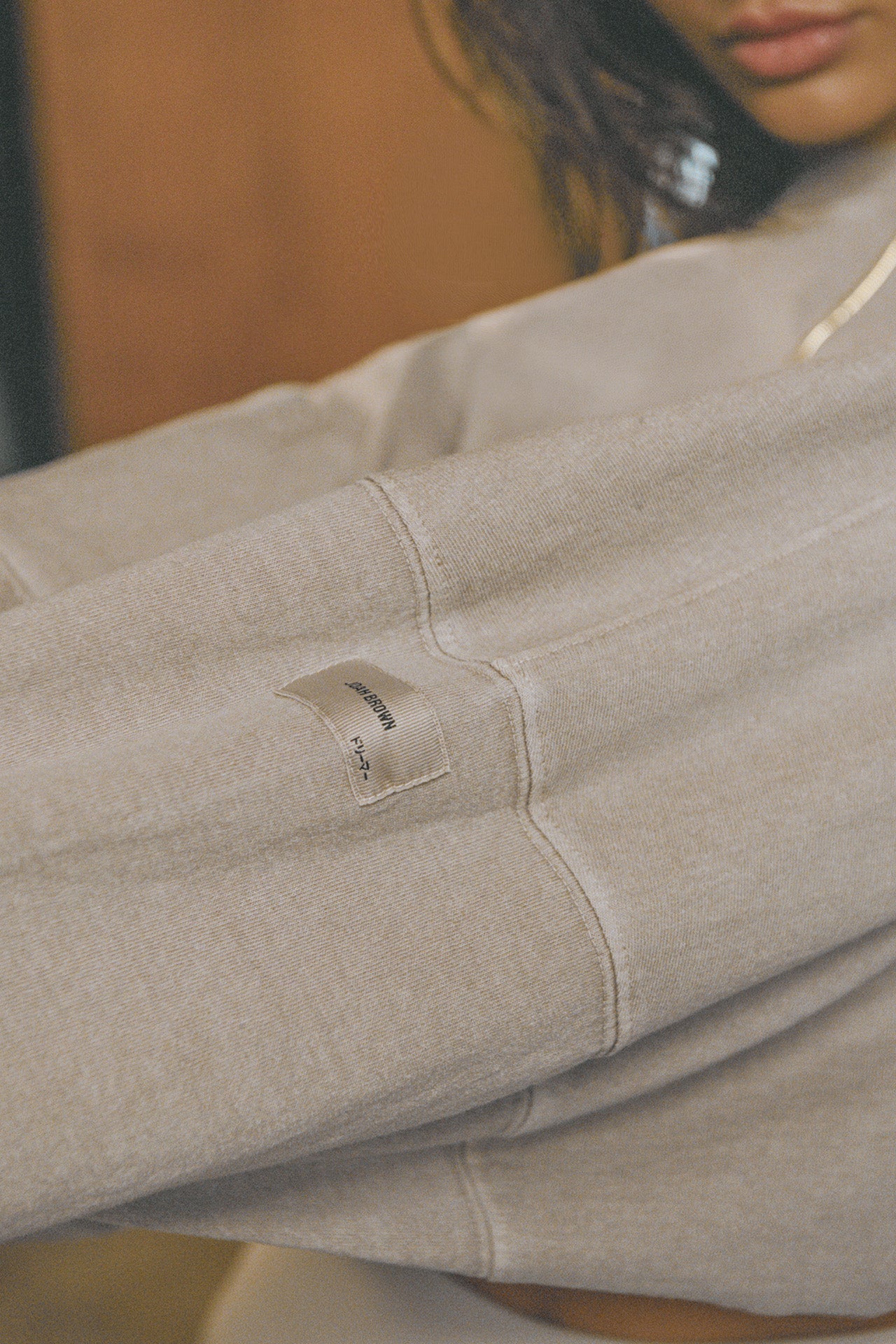 Close up detail side view of model posing in the cropped relaxed fit sandstone cotton Slouchy Crop Long Sleeve top with a crew neckline, dropped shoulders and oversized sleeves