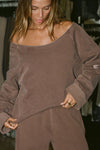 Front view of model posing in the oversized cedar french terry Slouchy Pullover Sweatshirt with a wide, off-the-shoulder neckline and a JOAH BROWN logo patch on the right sleeve