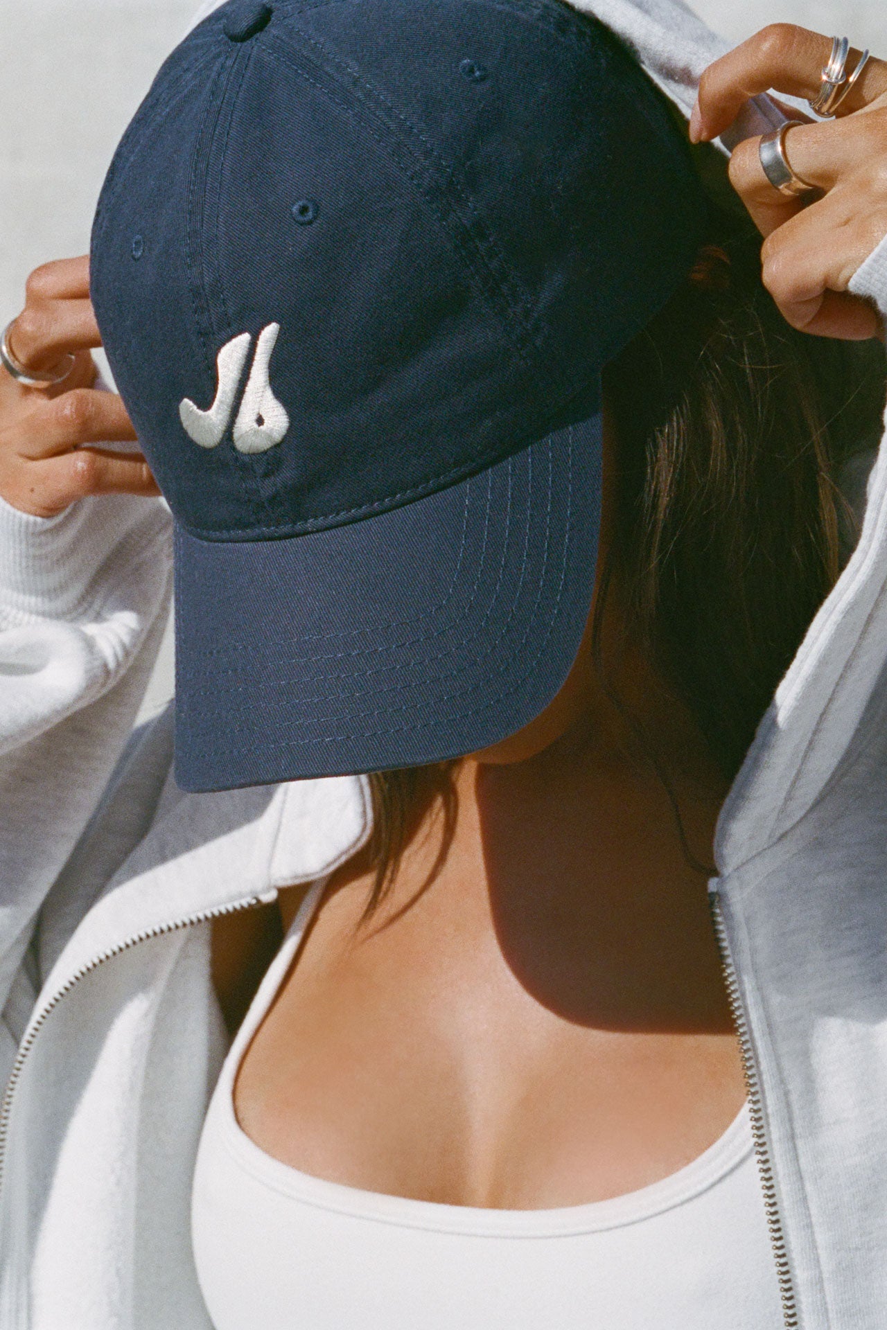 Close up side view of model posing in the structured six-panel navy The Classic Cap with a curved brim, adjustable back strap and an embroidered front and back Joah Brown logo