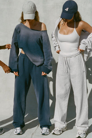 Two modes posing in a heritage washed navy french terry sweat set and a white sueded halter top and pearl french terry bottom set. 
