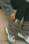 Close up side view of model adjusting the slouchy, pull on army luxe knit Leg Warmers that can be worn pulled up on scrunched down