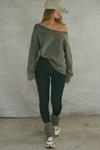 Full body front view of model posing in the oversized washed sage french terry Slouchy Pullover Sweatshirt with a wide, off-the-shoulder neckline and a JOAH BROWN logo patch on the right sleeve