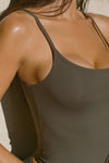 Close up detail side view of model posing in the soft and stretchy sueded carob Smoothing Cami with a scoop neckline and thin straps
