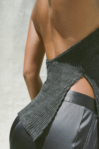 Close up detail side view of model posing in the ink luxe knit Split Front Halter Tank with an open back and side slits