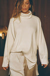 Front view of model posing in the relaxed and slouchy tunic-style natural luxe knit Turtleneck Tunic with dropped shoulders, side slits and adjustable ties for a customized shape