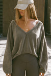 Front view of model posing in the slouchy oakmoss sherpa V Neck Pullover sweatshirt with a wide V-neckline that can be worn on or off the shoulders.