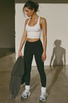 Full body front view of model posing in the fitted stretchy cropped white  flexrib Varsity Tank Bra with a scoop neckline