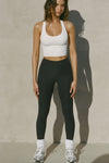 Full body front view of model posing in the sleek and stretchy full length sueded onyx The Body Legging with a mid-rise elastic waistband