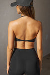 Back view of model posing in the sueded onyx Halter Scoop Bra top with an adjustable halter neck strap and open back