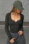 Front view of model  posing in the fitted vintage black Henley Long Sleeve with a notch in the scoop neckline