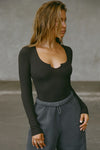 Front view of model posing in the fitted vintage black Henley Long Sleeve with a notch in the scoop neckline