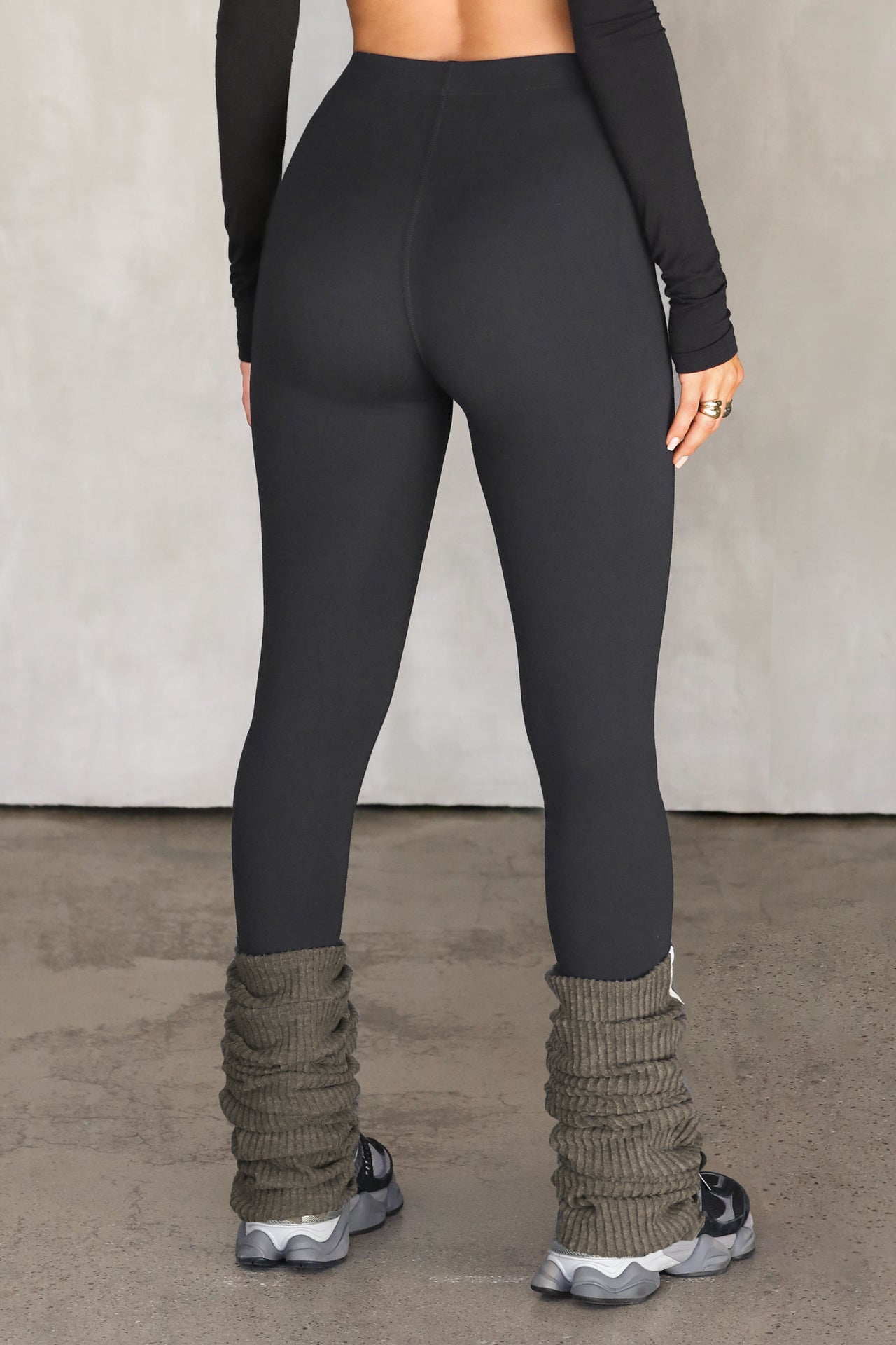 Back view of model from the waist down posing in the sleek and stretchy full length sueded onyx The Body Legging with a mid-rise elastic waistband