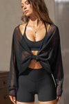 Front view of model posing in the sheer, relaxed fit black polka dot lace Knotted Crop Cardigan long sleeve top with an open front, and adjustable front tie that can be knotted at the center for a customizable fit and shape.