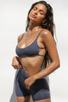 Front view of model posing in the stretchy minimal coverage sueded navy Cage Bra with thin straps and thin horizontal straps in the back
