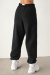 Back view of model from the waist down wearing the oversized loose fit black french terry Oversized Jogger with an elastic waistband and ankle cuffs