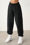 Front view of model from the waist down wearing the oversized loose fit black french terry Oversized Jogger with an elastic waistband and ankle cuffs