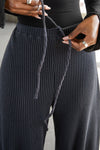 Close up detail front view of model from the waist down posing in the relaxed fit midnight luxe knit Relaxed Tapered Pant with a tapered leg, side pockets, hidden adjustable drawstring and subtle pleating at the sides for added shape and dimension.