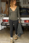 Full body front view of model posing in the fitted spruce Notched V Neck Long Sleeve top with a deep notched V-neckline, extra long sleeves and small side slits at the hem