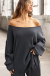 Front view of model posing in the relaxed fit midnight luxe knit Off Shoulder Tunic with a wide off-the-shoulder neckline and asymmetrical hem