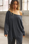 Front view of model posing in the relaxed fit midnight luxe knit Off Shoulder Tunic with a wide off-the-shoulder neckline and asymmetrical hem