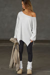 Full body front view of model posing in the relaxed fit pearl grey luxe knit Off Shoulder Tunic with a wide off-the-shoulder neckline and asymmetrical hem