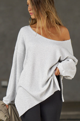 Front view of model posing in the relaxed fit pearl grey luxe knit Off Shoulder Tunic with a wide off-the-shoulder neckline and asymmetrical hem