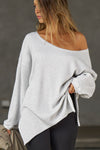 Front view of model posing in the relaxed fit pearl grey luxe knit Off Shoulder Tunic with a wide off-the-shoulder neckline and asymmetrical hem