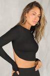 Side view of model posing in the fitted and cropped black modal Open Boatneck Long Sleeve top with a high neckline,curved hem, open back and adjustable strap details