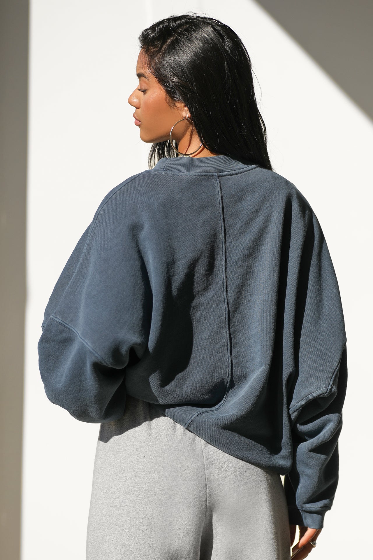 Back view of model posing in the relaxed fit washed navy french terry Oversized Crew Pullover sweatshirt with dropped sleeves and a ribbed crew neckline