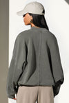 Back view of model posing in the relaxed fit washed sage french terry Oversized Crew Pullover sweatshirt with dropped sleeves and a ribbed crew neckline