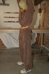 Full body side view of model posing in the relaxed fit cedar french terry Oversized Straight Leg Jogger with an elastic waistband, hidden drawstring, pocket details. and adjustable cinching at the ankle cuffs