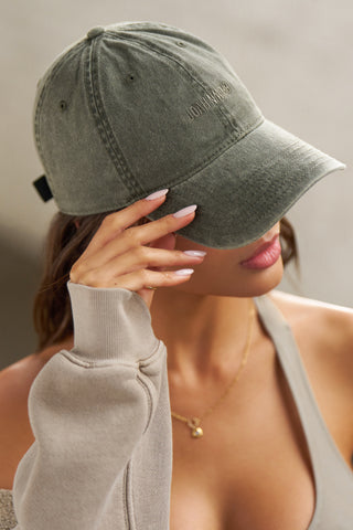 Front view of model posing in the six-panel washed green Official Cap with a curved brim and an embroidered upside down Joah Brown logo on the front