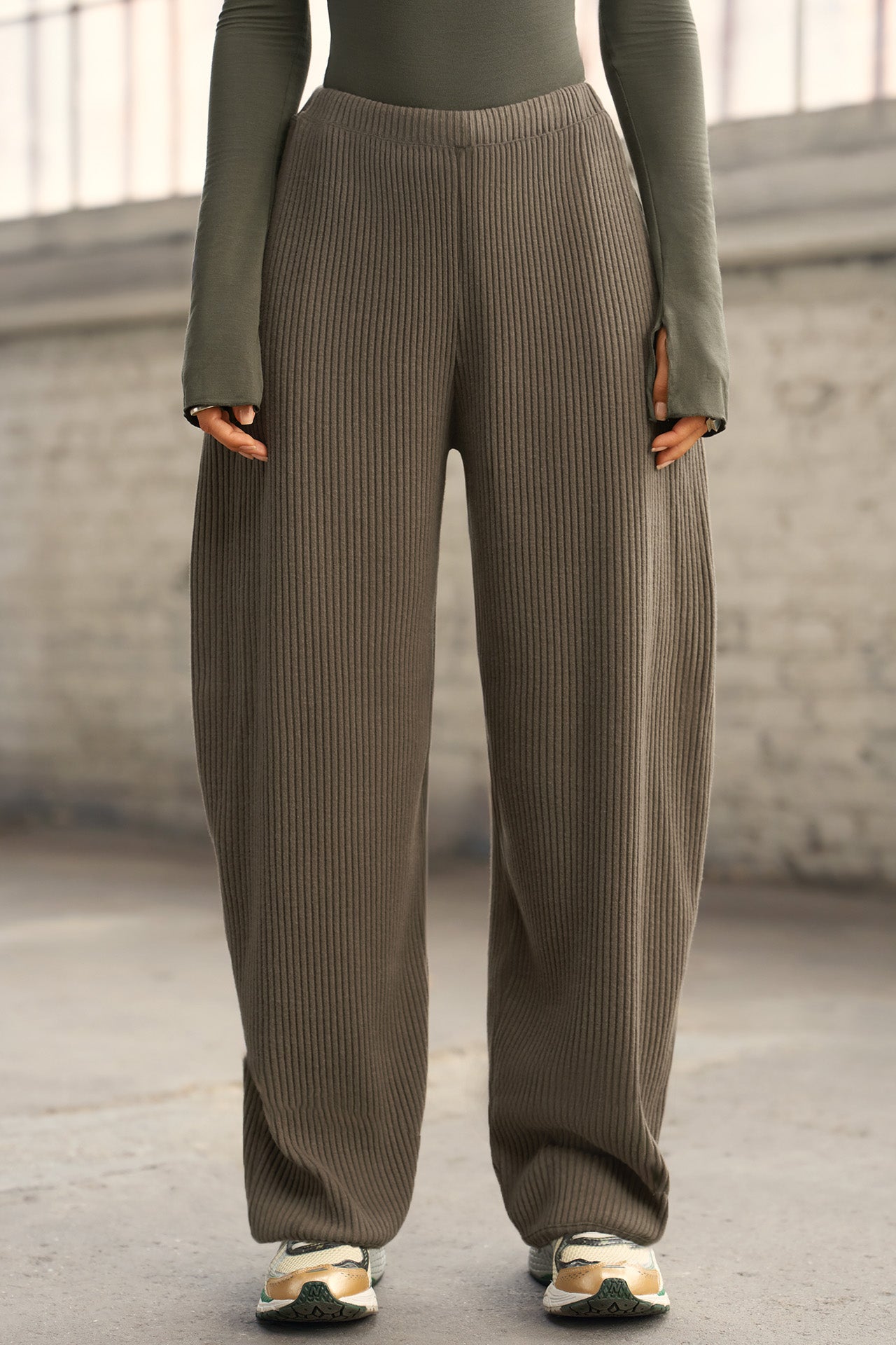 Front view of model from the waist down posing in the relaxed fit army luxe knit Relaxed Tapered Pant with a tapered leg, side pockets, hidden adjustable drawstring and subtle pleating at the sides for added shape and dimension.