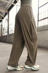 Side view of model from the waist down posing in the relaxed fit army luxe knit Relaxed Tapered Pant with a tapered leg, side pockets, hidden adjustable drawstring and subtle pleating at the sides for added shape and dimension.