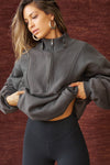 Front view of model posing in the oversized comfortable charcoal luxe french terry Retro Half Zip pullover sweatshirt with ribbed accents on the chest and sleeves, a hidden kangaroo pocket and a half zip collar